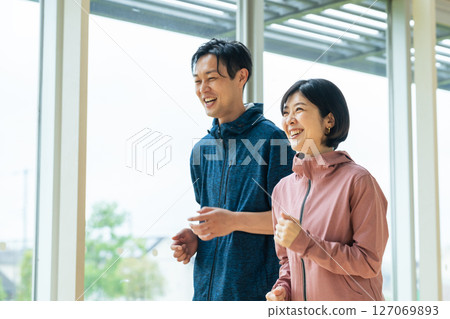 Middle-aged couple running indoors Middle-aged couple running indoors 127069893