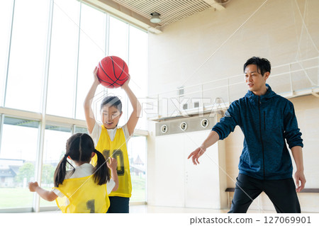 孩子們在打籃球，一名男子在指導他們 127069901