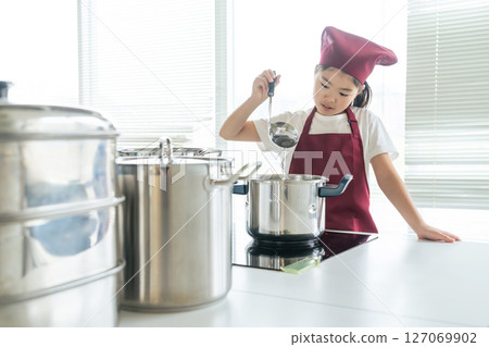 A girl wearing an apron cooking in the kitchen 127069902