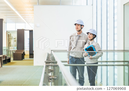 男工程師和女工程師站在室內,手裡拿著一台平板電腦 男工程師和女工程師站在室內,手裡拿著一台平板電腦 127069908