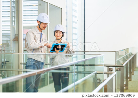 男性工程師和女工程師一邊查看平板電腦，一邊檢查建築物內部 127069909