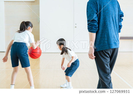 Children playing basketball and a man coaching them 127069931