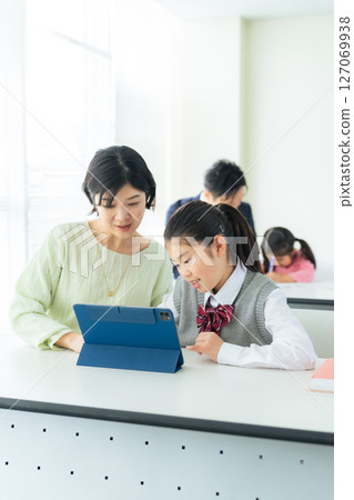 A female teacher instructing a girl using a tablet 127069938