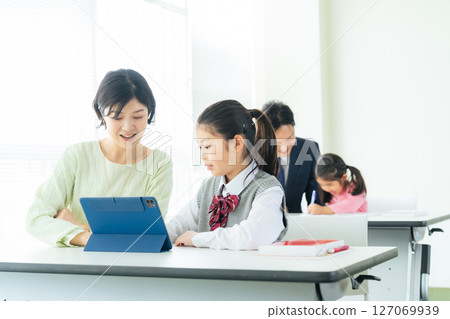 A female teacher instructing a girl using a tablet 127069939
