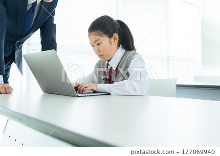 一名女孩在教室裡向一名男老師學習如何使用電腦 127069940