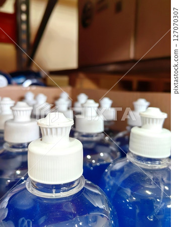 close-up blue liquid bottles stored on shelves in stockroom during daylight hours. 127070307