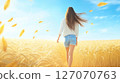 Woman walking through a wheat field in autumn 127070763