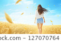 Woman walking through a wheat field in autumn 127070764