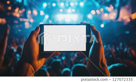 person holding smartphone with blank screen in concert atmosphere. vibrant lights create exciting mood 127072335
