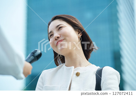 Young woman being interviewed outdoors 127072411