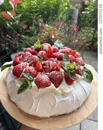 Strawberry pavlova cake decorated with fresh mint leaves and powdered sugar 127073138
