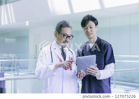 A portrait of two doctors talking while looking at a tablet in a hospital. Photo courtesy of Sky Perfect TV Tokyo Media Center. 127073226