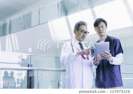 A portrait of two doctors talking while looking at a tablet in a hospital. Photo courtesy of Sky Perfect TV Tokyo Media Center. 127073228