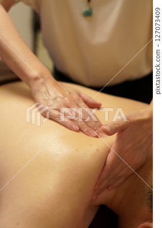 女治療師抬起肩部肌肉並將背部肌肉拉向肩部的技術 127073409