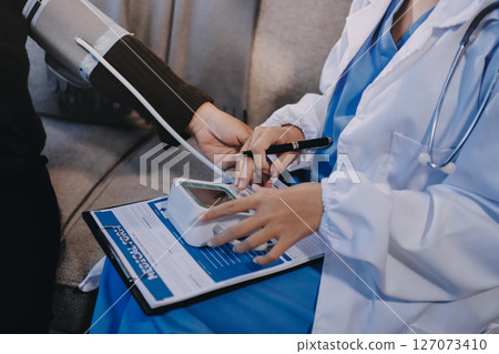 Doctor using Blood pressure monitor and stethoscope checking measuring arterial blood pressure on arm to a patient in the hospital, healthcare and medical concept 127073410