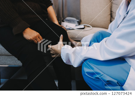 Young doctor examines senior patient's leg 127073424