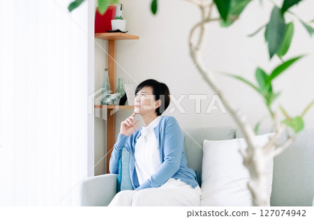Middle-aged woman thinking in the living room Middle-aged woman thinking in the living room 127074942