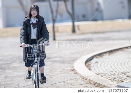 A student riding a bicycle wearing a coat 127075507