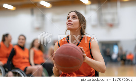 Determined Athlete in Wheelchair Basketball Preparing to Shoot during Intense Game Practice Determined Athlete in Wheelchair Basketball Preparing to Shoot during Intense Game Practice 127075562