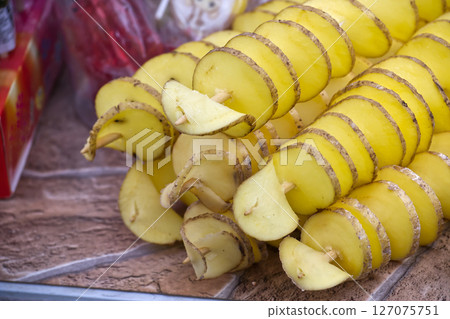 Close-up of spiral-cut tornado potatoes on skewers presents a delicious street food snack. 127075751