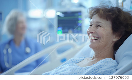 Happy senior woman smiles in hospital bed with caring nurse in background during cheerful moment 127076003