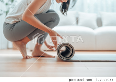 Young Asian woman doing yoga, twisting on a mat in the living room Young Asian woman doing yoga, twisting on a mat in the living room 127077033