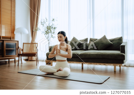 Young Asian woman meditating in lotus position at home 127077035