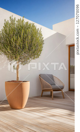 Cozy outdoor space featuring a potted tree and a comfortable chair under a clear blue sky Cozy outdoor space featuring a potted tree and a comfortable chair under a clear blue sky 127078096