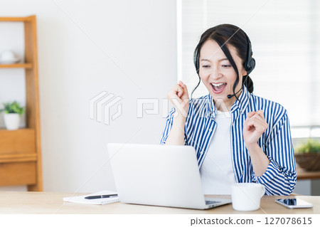 A middle-aged woman who has online English conversation in the living room. 127078615