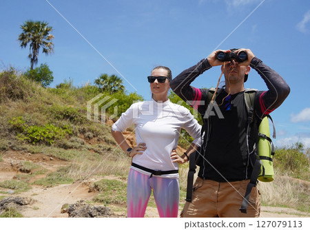 A man and a woman are intently looking through binoculars at something interesting in the distance 127079113