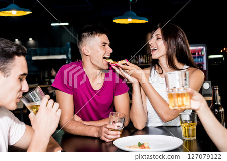 Cheerful friends in the pub. Drinking beer, eating pizza, talking, having fun. 127079122