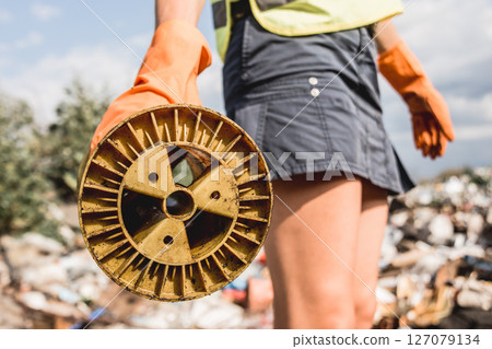 Woman volunteer helps clean the field of nuclear waste and plastic garbage.  127079134