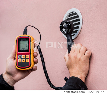 Technician use hand-held anemometer measuring air flowing measurement 127079144