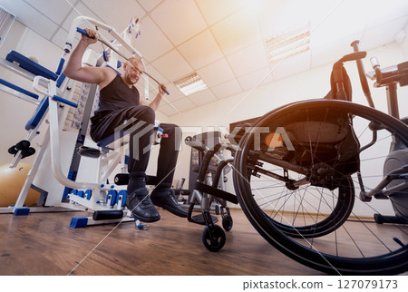 Disabled man doing strength exercises separate from the wheelchair. Disabled man doing strength exercises separate from the wheelchair. 127079173
