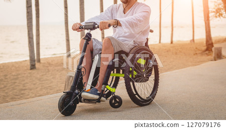 Disabled man in a wheelchair with electric scooter on the beach Disabled man in a wheelchair with electric scooter on the beach 127079176