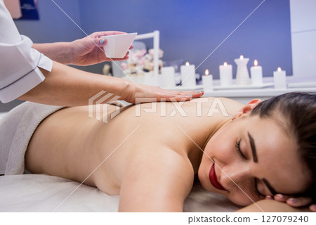 Beautiful young woman enjoying massage in spa salon. Cosmetology 127079240