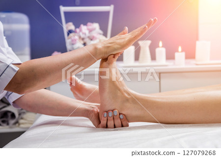 Beautiful young woman enjoying foot massage in spa salon. Cosmetology 127079268