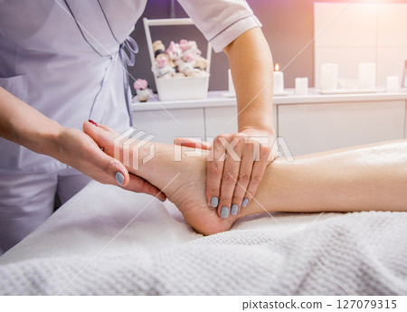 Beautiful young woman enjoying foot massage in spa salon. Cosmetology Beautiful young woman enjoying foot massage in spa salon. Cosmetology 127079315