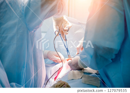 Surgeon and assistants in operating room with surgery equipment. 127079535