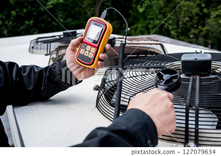 Technician use hand-held anemometer measuring air flowing measurement 127079634