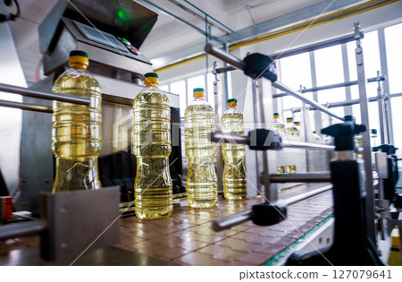 Bottling line of sunflower oil in bottles. Vegetable oil production plant. Bottling line of sunflower oil in bottles. Vegetable oil production plant. 127079641