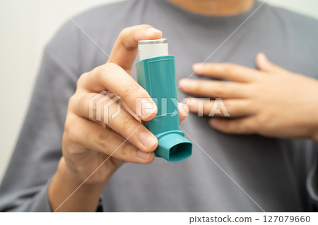 Asthma and chronic obstructive pulmonary disease COPD, Asian young man using metered dose inhaler MDI. 127079660