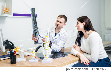 Traumatologist showing MRI film to patient in hospital. 127079720