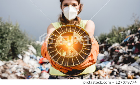 Woman volunteer helps clean the field of nuclear waste and plastic garbage. 127079774