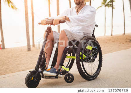 Disabled man in a wheelchair with electric scooter on the beach 127079789