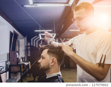 Young man with trendy haircut at barber shop. Young man with trendy haircut at barber shop. 127079802