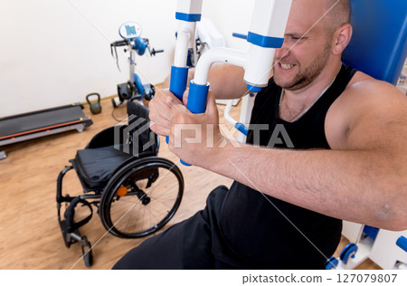 Disabled man doing strength exercises separate from the wheelchair. Disabled man doing strength exercises separate from the wheelchair. 127079807