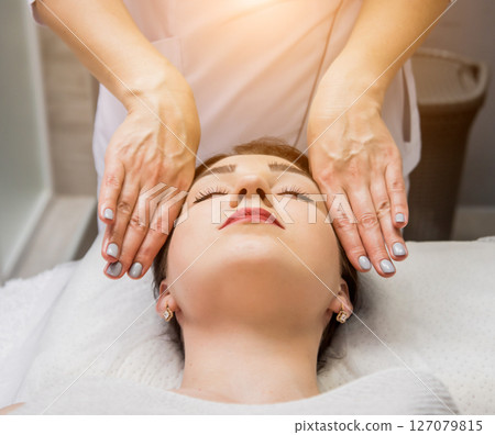 Beautiful young woman enjoying head massage in spa salon. Cosmetology Beautiful young woman enjoying head massage in spa salon. Cosmetology 127079815