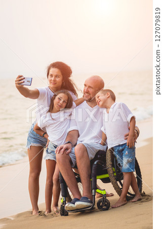 Disabled man in a wheelchair with his family on the beach. Disabled man in a wheelchair with his family on the beach. 127079819