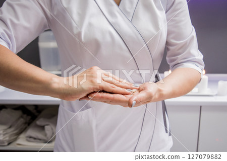 Masseur putting aroma oil on her hands, preparing for massage in spa center 127079882